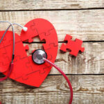 Breakthrough Drugs Slash Heart Attack Risk Red heart puzzle with stethoscope on wooden background