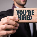 ICE Hiring DISASTER — 200 Criminals Slip Through Person holding a Youre Hired sign.