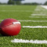 Game Day Bloodbath Shocks College Football A red American football resting on a green artificial turf field