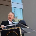 Bill Maher SLAMS Party—Leftward Lurch Exposed A man in formal attire speaking at a podium during a Hollywood Walk of Fame ceremony