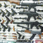 SHOCKING DISCOVERY–Funding SOURCE of School Shooter’s Guns Wall display of various firearms in a store.