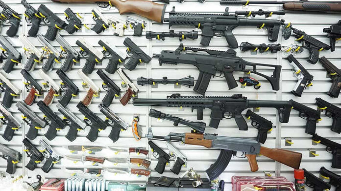 1096565825 Wall display of various firearms in a store.