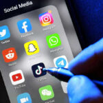 TikTok Star’s Tragic End Stuns Millions Social media apps on phone screen with hand holding stylus.
