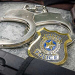 Philadelphia Terror Spree FINALLY Ends Handcuffs, officer badge, and firearm on textured surface.