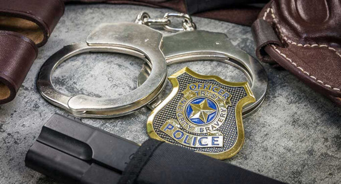 1939544200 Handcuffs, officer badge, and firearm on textured surface.