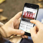 Explosive Report — Crime Numbers Fabricated? Person holding smartphone displaying fake news notification.