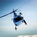 Helicopters Collide Midair—UNTHINKABLE CAUSE A helicopter flying over a mountainous landscape against a blue sky