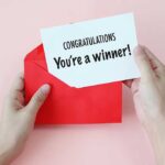 92-Year-Old Gaming Phenom Stuns Esports World Hands holding a congratulations card and a red envelope
