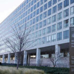 DOT TARGETS Blue State–Who Will BLINK? Orville Wright Federal Building with flags outside.