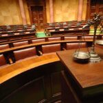 Former Anchor KILLS Mother — Escapes Trial A courtroom with empty seats and a scale of justice in the foreground