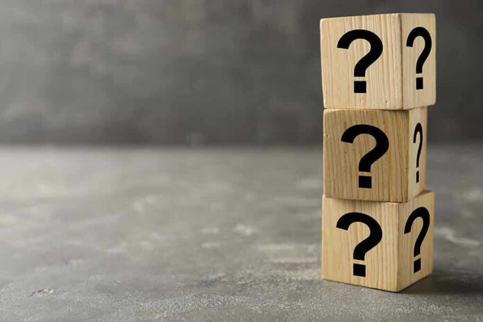 Three wooden blocks with black question marks stacked.