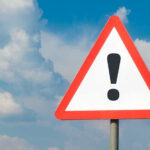 US Sends BLUNT MESSAGE to International Energy Agency Warning sign with exclamation mark against cloudy sky.