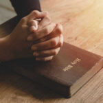 Immigration SIN Claim EXPLODES — Churches Erupt Hands praying on a Bible.
