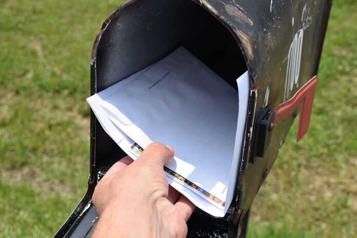 2318351967 Hand placing mail in a black mailbox.