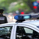 Rookie Officer Gunned Down–Why? Police car and officer on a city street.