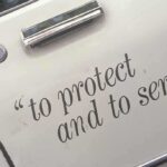 Close-up of a police car door with the phrase to protect and to serve
