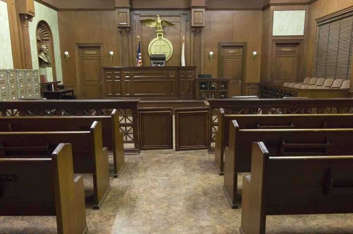 shutterstock_121502665.jpg Interior view of an empty courtroom with wooden benches and a judges bench