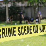 Yellow crime scene tape blocking grassy area.