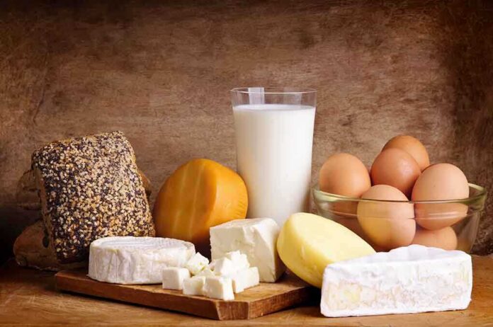 Assorted dairy products including cheese, milk, and eggs on a wooden surface