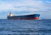 A large cargo ship sailing on the ocean under a blue sky