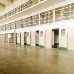 Interior view of a prison cell block with empty cells and security bars
