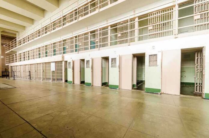 shutterstock_206092135.jpg Interior view of a prison cell block with empty cells and security bars