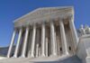 The Supreme Court building featuring grand columns and statues under a clear blue sky