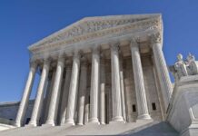 The Supreme Court building featuring grand columns and statues under a clear blue sky