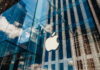 Apple store with glass facade and city reflections.