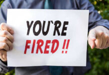 Person holding YOURE FIRED sign.