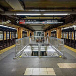 Subway station platform with directional signs overhead.