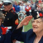 Elderly women in military attire saluting during a veterans ceremony