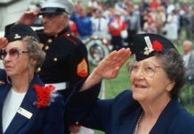 Elderly women in military attire saluting during a veterans ceremony