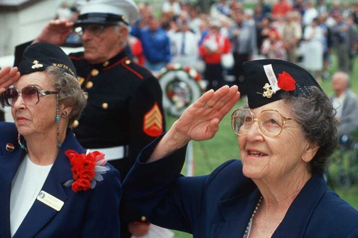 Elderly women in military attire saluting during a veterans ceremony
