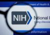 NIH logo displayed on a digital screen, viewed through a magnifying glass