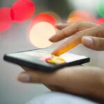 A person using a smartphone with a colorful bokeh background