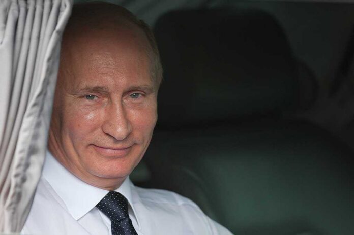 A smiling man in formal attire sitting inside a car with curtains