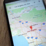TECH GIANT Caught Altering Burned Lands Smartphone displaying map of Los Angeles, California.