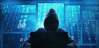 Person in hoodie using a laptop with digital code.