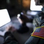 Moral Crisis: Pope’s Radical Move on AI Soldier using laptop with US flag patch visible.