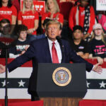 Trump ENDS Colbert And Has The Last Laugh Politician speaking at rally with supporters behind him.
