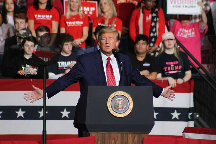 1662925921 Politician speaking at rally with supporters behind him.