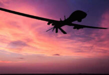Musk’s Starlink Sparks Pentagon Drone Clash Silhouette of a drone against a colorful sunset.