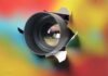 AI Snooping – HOW Your Boss Is Watching Camera lens emerging through torn colorful paper