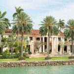 Billionaire’s $7.2M Regret: Shocking PAYOUT A luxurious mansion surrounded by palm trees and a waterfront view