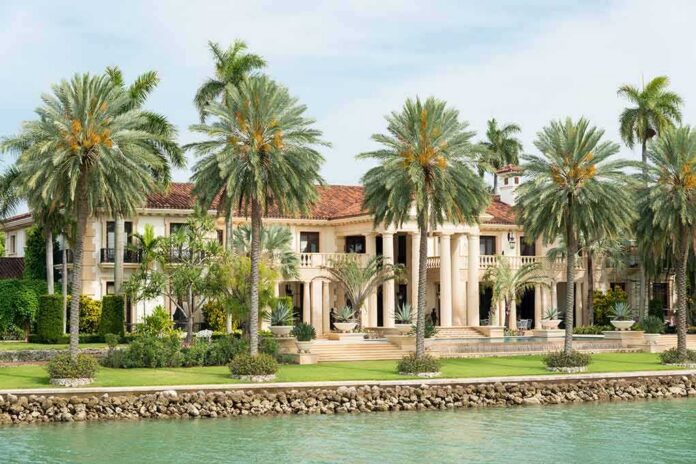 A luxurious mansion surrounded by palm trees and a waterfront view