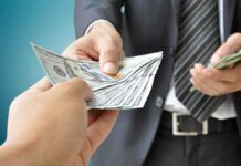 DHS Secrets: Warehouse SCANDAL Exposed Two hands exchanging cash in a business setting
