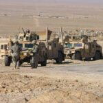 Two military humvees with soldiers in a desert landscape