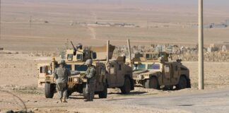 Two military humvees with soldiers in a desert landscape