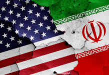 Before you believe it, check what’s signed. Cracked American and Iranian flags painted on a wall.